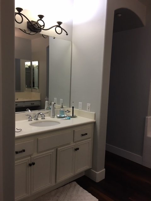Mike's side of the bathroom features a wall mirror and yellowing corian.