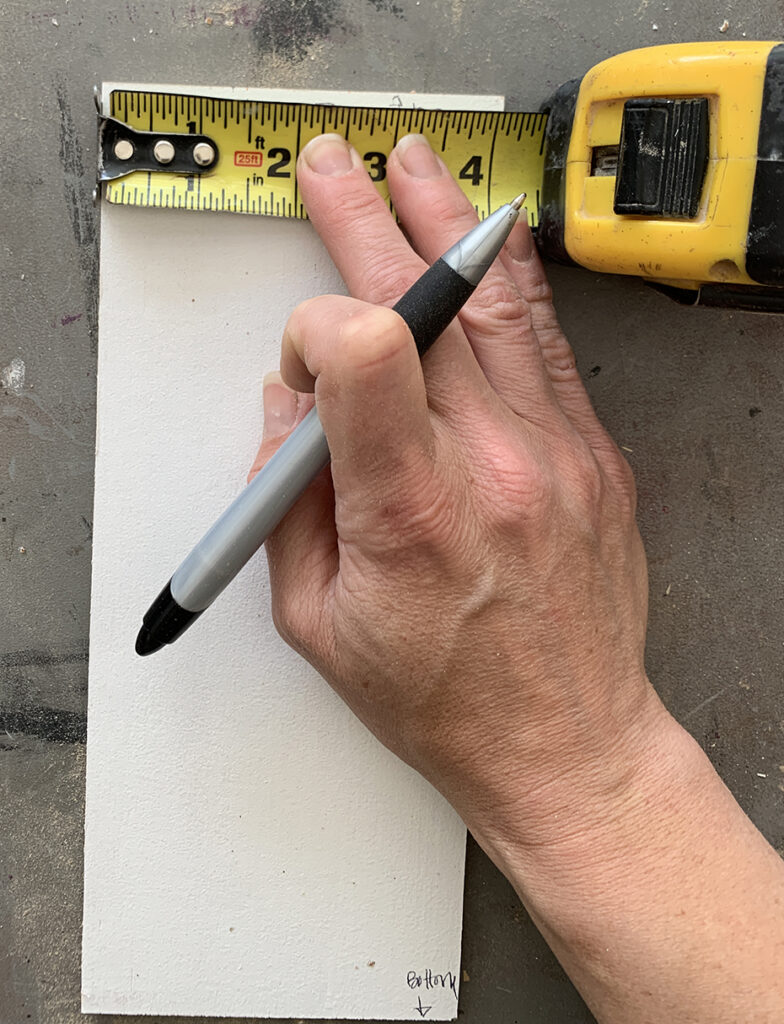 Joannie holding measuring tape against 1/4" wood to place mark for Ikea template at 1 5/16"