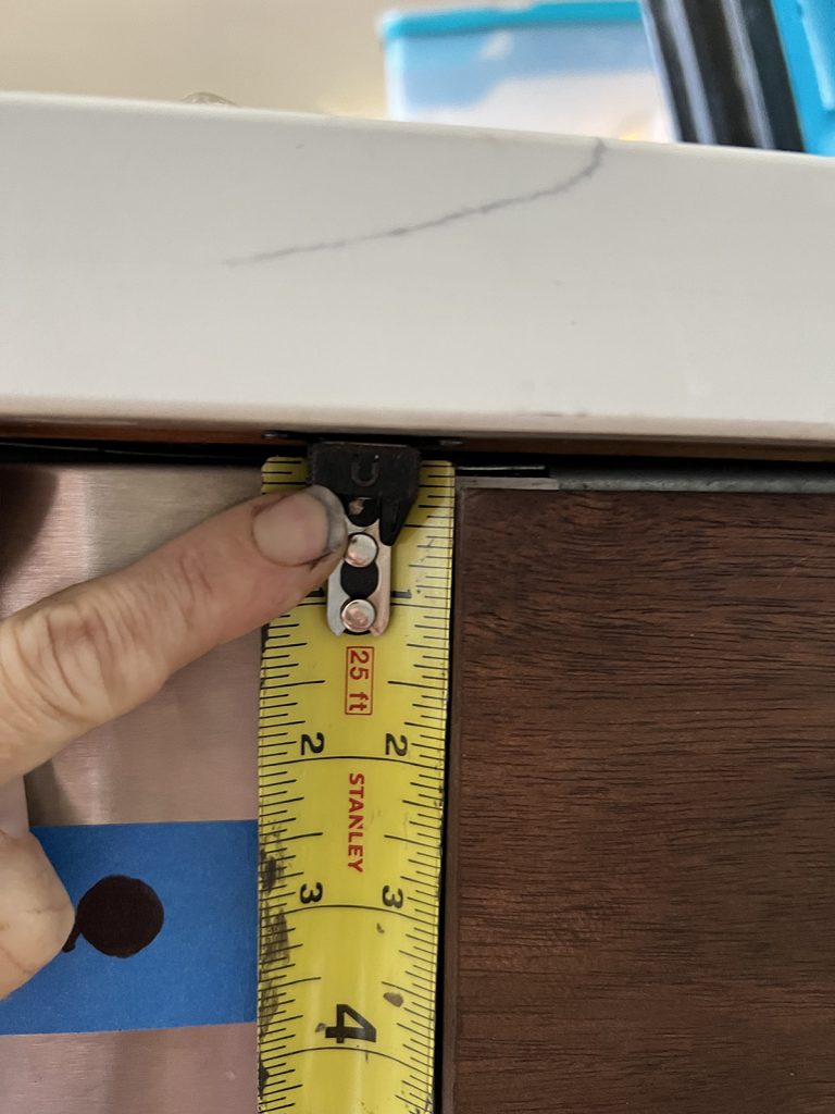 close up of my tape measure and space between the counter top and the cabinet door