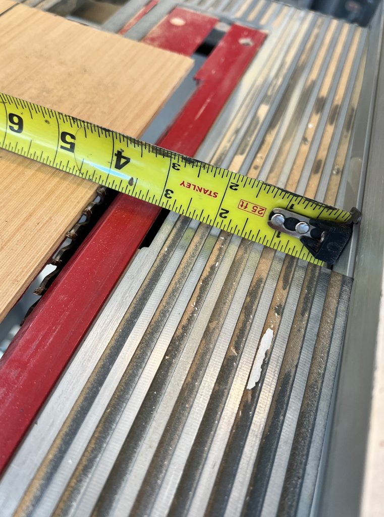 close up view of the measuring tape and the saw blade. the saw blade is raised just enough to cut a groove in the board but not through it.