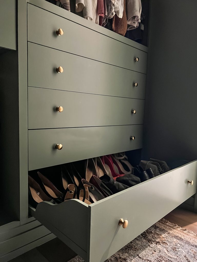 up close picture of joannie's shoe storage drawer with bracket supports she added for the slab drawer front with gold brass pull hardware and slab drawer front all painted carolina gull by benjamin moore.